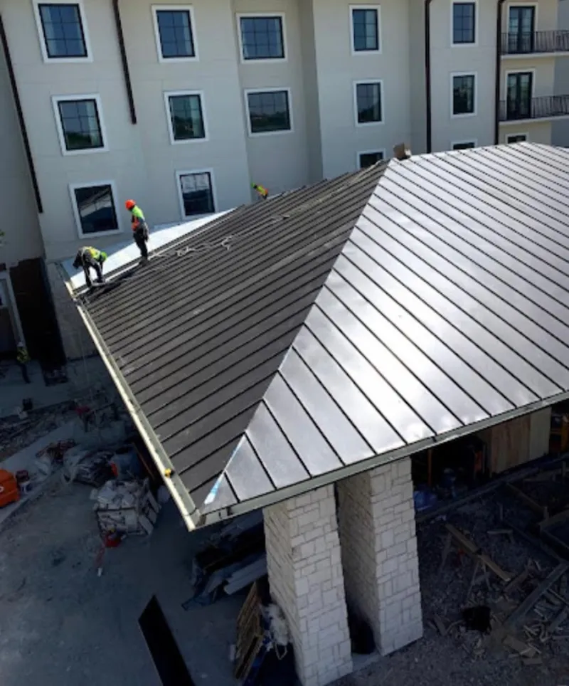 Crew installing standing seam metal roof panels on a commercial project in Bellbrook